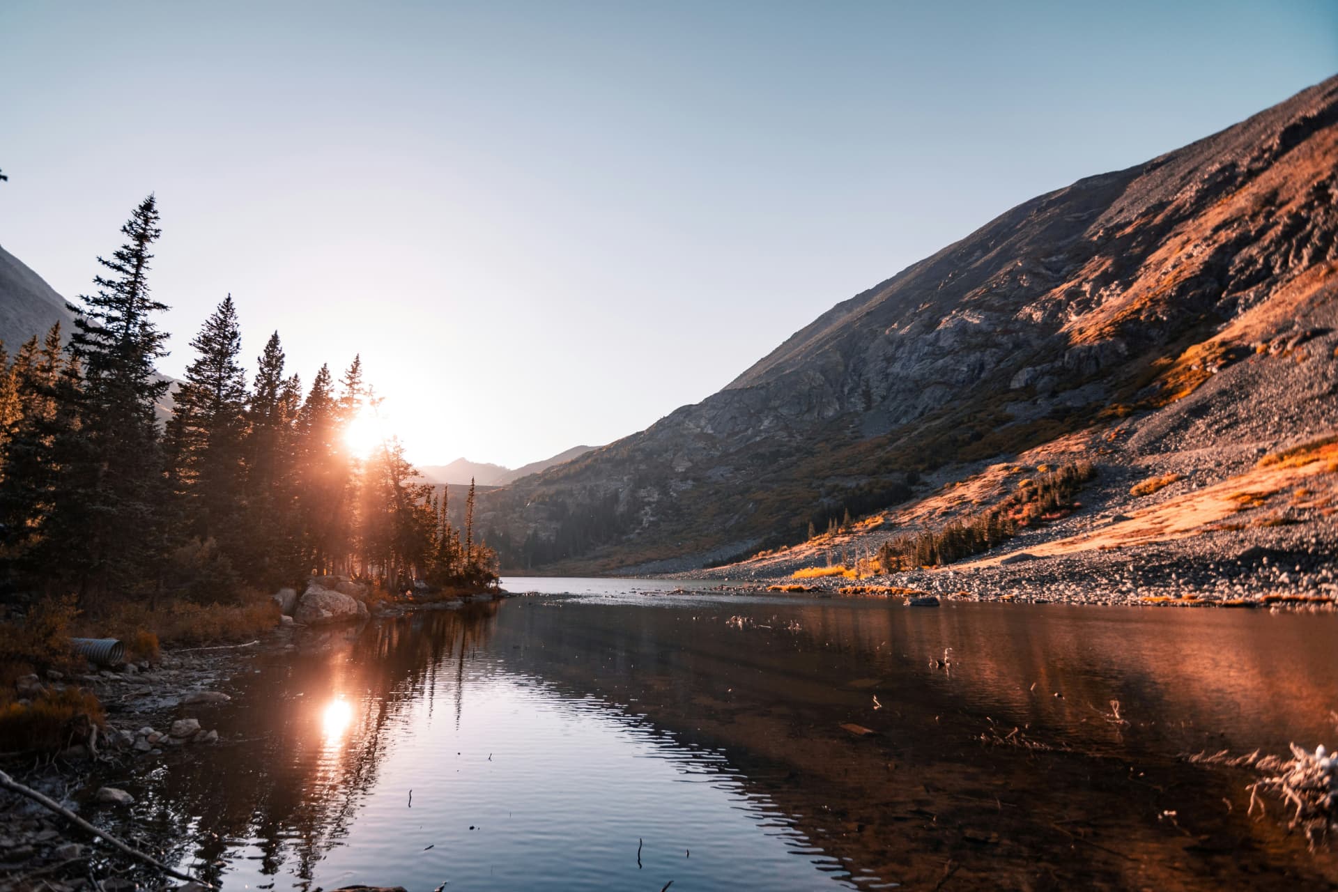 Sunlit lake between forested mountains
